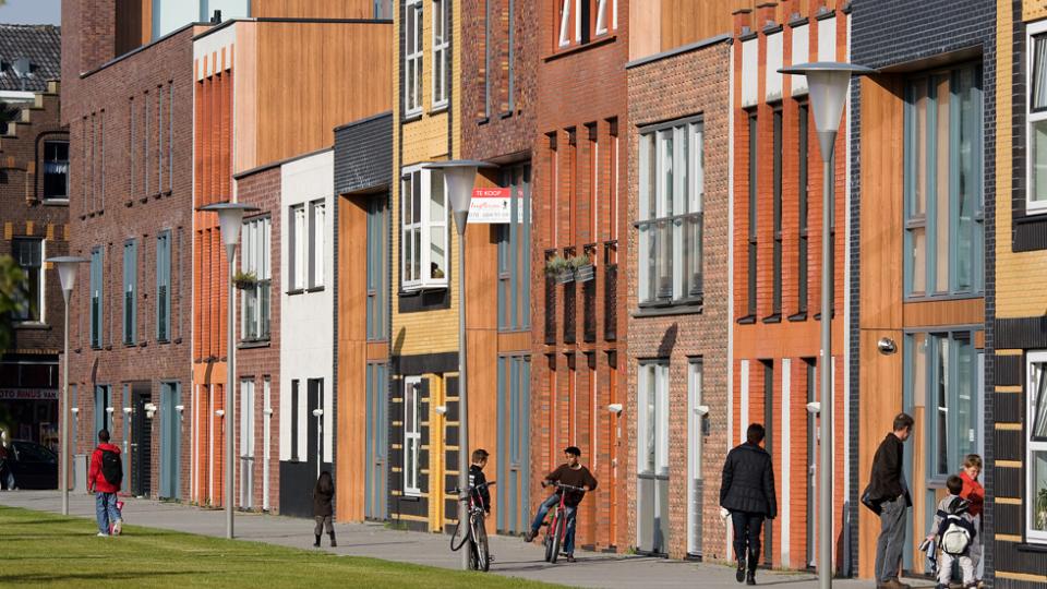 Photo of a street with houses and people walking by